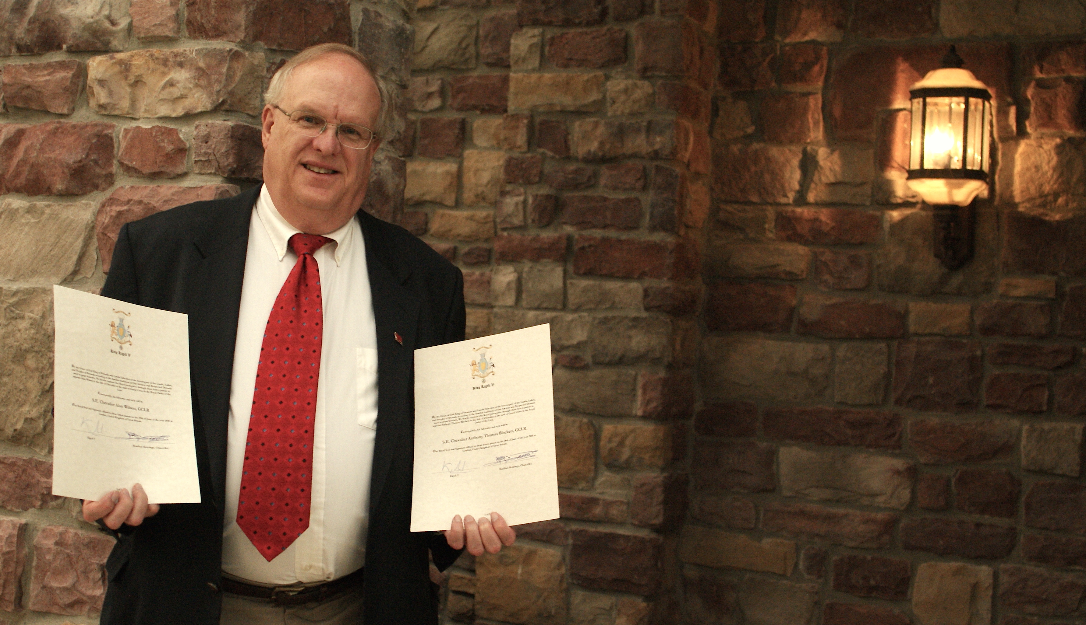 George Horwatt, President of The Welsh Cultural Endeavor of Northeastern Pennsylvania, holds proclamations signed by King Kigeli V of Rwanda to knight Welsh Researchers Alan Wilson and Baram Blackett.